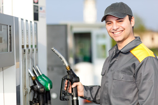 Smiling Employee Holds Pump At Gas Station